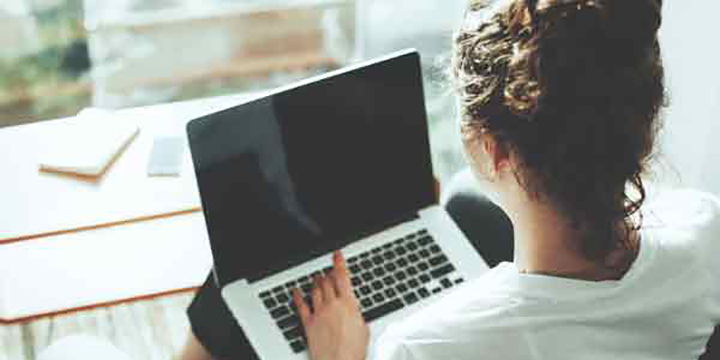 A back view of a woman typing on her laptop